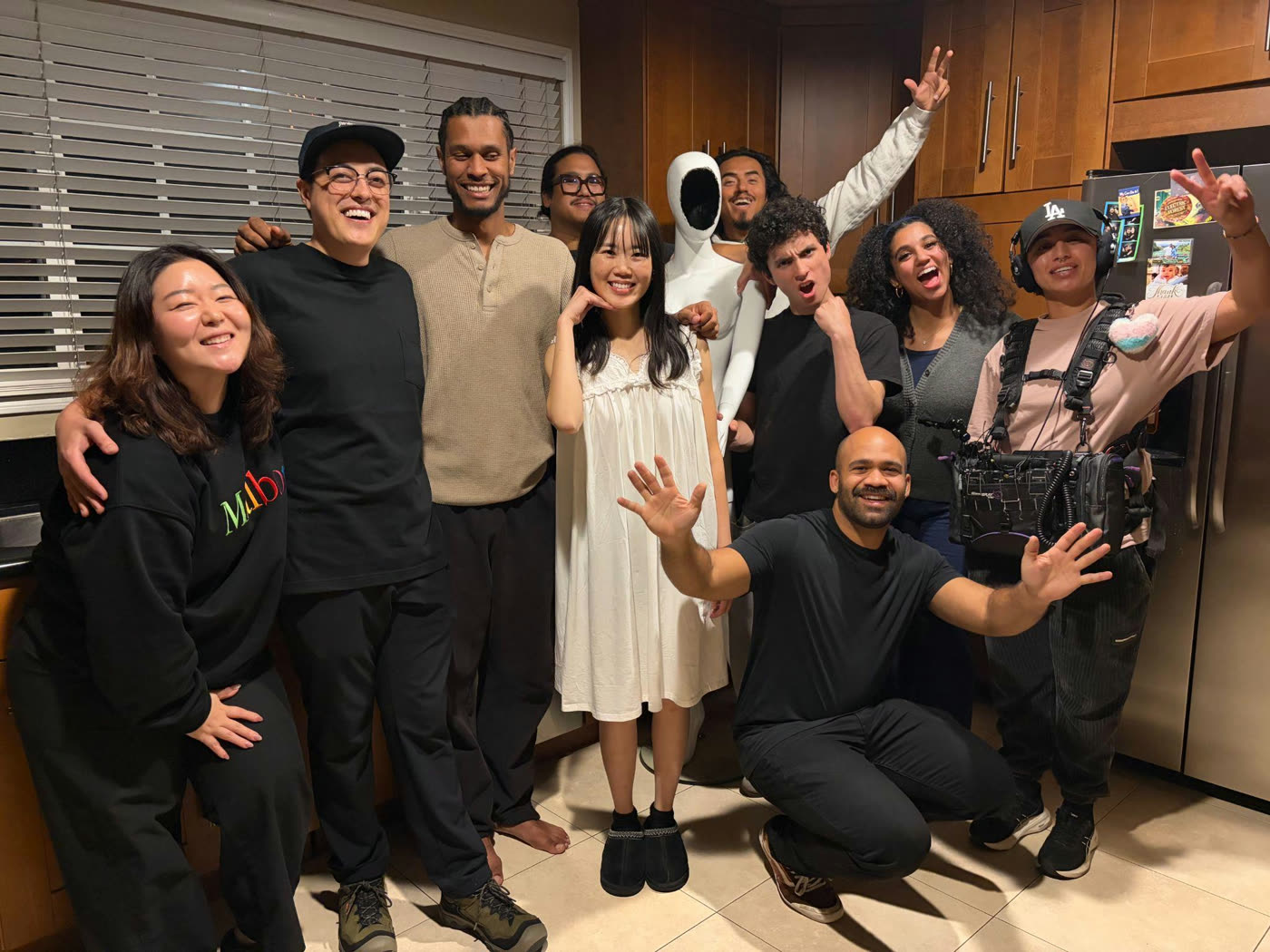 The full cast and crew crowded into the kitchen, mid-laugh.